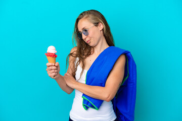 Young caucasian woman holding ice cream and wearing a beach towel isolated on blue background with sad expression