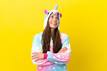 Girl with unicorn pajamas over isolated background looking up while smiling