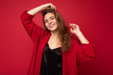 Obraz na płótnie Canvas Young beautiful european stylish brunette woman wearing black blouse top and red cardigan isolated over red background with positive sincere emotions. Simple and natural looking at the camera. Free