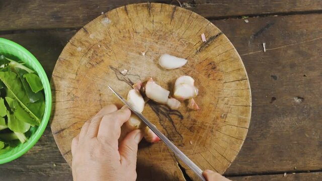 Old asian slicing galangal with knife on her hands. Preparing for making food menu. Thai food. Top View.