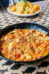 Traditional greek recipe made with octopus, feta cheese and boiled tomatoes cooked in a vintage pan for a mediterranean meal