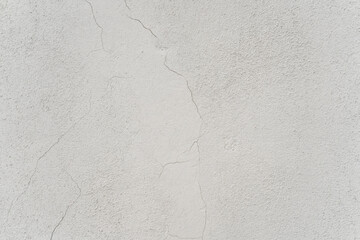Exterior white wall with cracks in the paintwork. Texture wallpaper background.