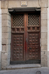 Old wooden paneled door with metal rivets at the entrance of an old building in the center of Madrid.