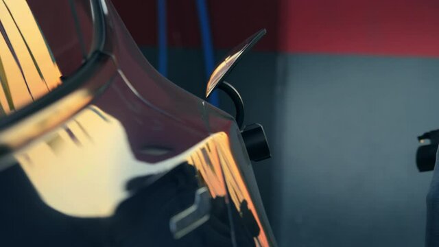 Hand unplugging electric charging plug out of electric car charge port at charging station. Closeup.