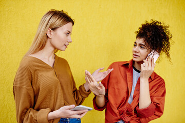 Thoughtful women talking near bright wall