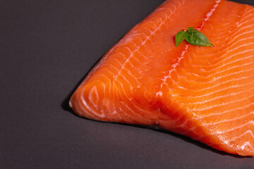 Fresh raw salmon or trout sea fish fillet on black stone background