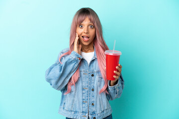 Young mixed race woman drinking a fresh drink isolated on blue background with surprise and shocked facial expression