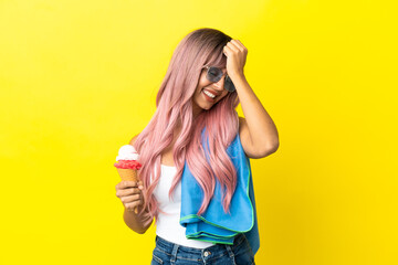 Young mixed race woman with pink hair holding ice cream isolated on yellow background has realized something and intending the solution