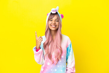Young mixed race woman wearing a unicorn pajama isolated on white background pointing with the...
