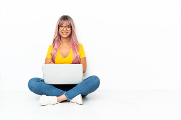 Young mixed race woman with a laptop with pink hair sitting on the floor isolated on white...