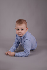 charming little preschool boy in white pants and blue shirt on gray background. child, kid