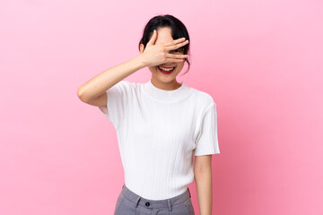 Young Vietnamese woman isolated on pink background covering eyes by hands and smiling