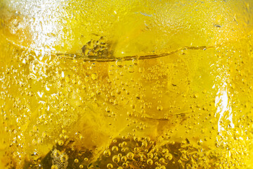 Yellow bubble of water on ice in a glasses beer or whisky. background texture.