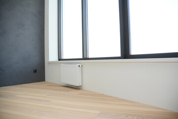 An empty modern apartment with oak hardwood flooring, gray plastered wall, large windows and a...