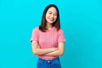 Young Vietnamese woman isolated on blue background keeping the arms crossed in frontal position