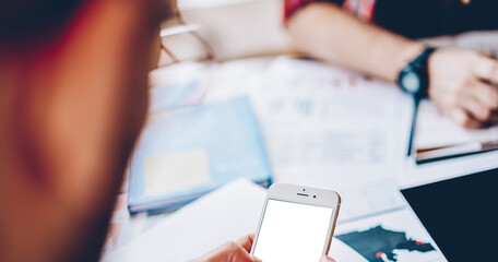 Unrecognizable man using blank smartphone device for browsing web advertising during brainstorming meeting for learning together, selective focus on mockup mobile technology with copy space area