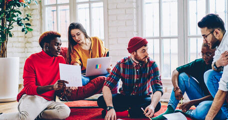 Diverse male and female colleagues cooperate on startup project during freelance meeting for brainstorming, team of creative graphic designers communicate about distance task in stylish flat
