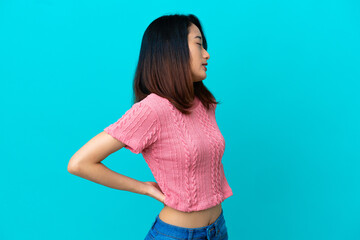 Young Vietnamese woman isolated on blue background suffering from backache for having made an effort