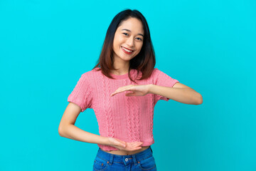 Fototapeta na wymiar Young Vietnamese woman isolated on blue background holding copyspace imaginary on the palm to insert an ad