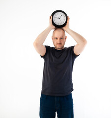 Deadline concept. A man in a T-shirt holds a large clock. Isolated on a white background.