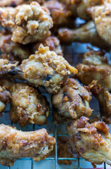 Plenty of pieces of chicken drumsticks are piled up on the grill.