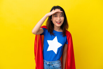 Super hero Vietnamese woman isolated  on yellow background looking far away with hand to look...