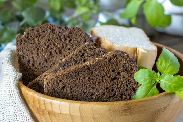 sliced rye bread in a wooden bowl and a sprig of basil