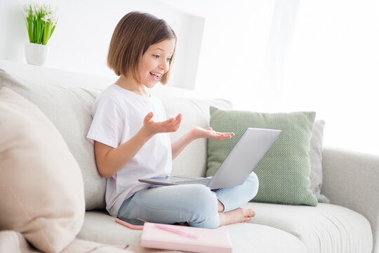 Photo portrait little girl sitting on couch talking on web camera