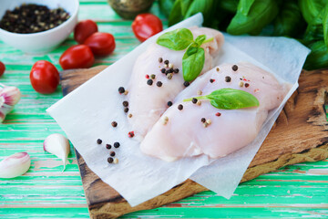 Raw chicken breast marinated for baking on a wooden board