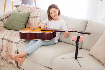 Full body photo of young cheerful girl happy positive smile online lesson learn play guitar sit...
