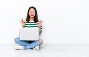 Naklejka premium Young Vietnamese woman with a laptop sitting on the floor isolated on white wall showing an ok sign with fingers