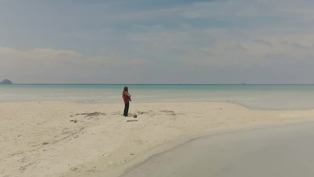 man with dreadlocks playing guitare on seascape- drone view