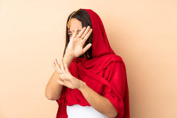 Young Indian woman isolated on beige background nervous stretching hands to the front