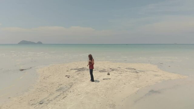 man with dreadlocks dancing and singing on seascape- drone view