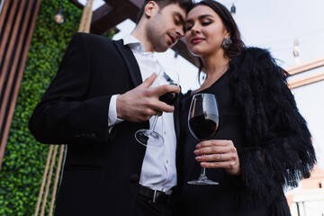 low angle view of couple holding glasses of red wine