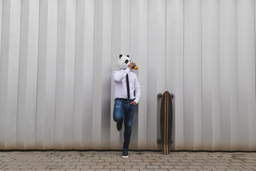 Businessman with a longboard skateboard and panda bear mask having coffee