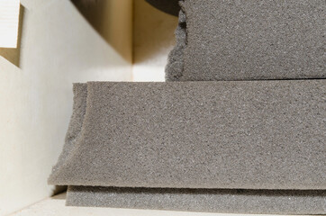 pieces of thick gray sponge foam in a room.  three thick stacked with rough edges