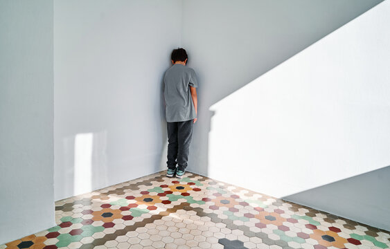 Lonely sad kid standing in corner