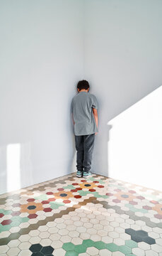 Lonely sad kid standing in corner