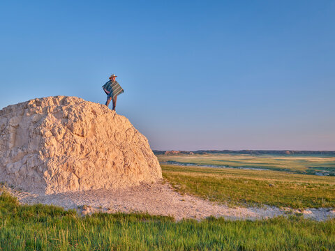 Man in a Mexican poncho and cowboy hat is enjoying summer sunrise at prairie - Pawnee National Grassland in Colorado