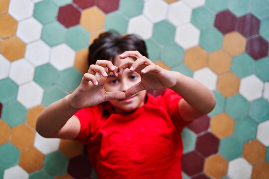 Smiling kid showing heart gesture
