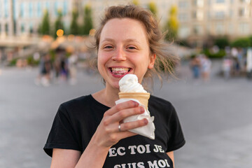 A young woman is holding, eating and enjoying an ice-cream cone
