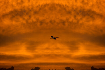 Commercial airplane flying through clouds in dramatic sunset light. Travel concept