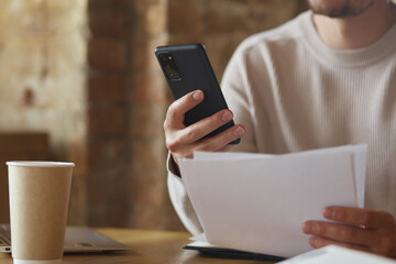 Focused young businessman holding financial document with trading statistics and investments profit...