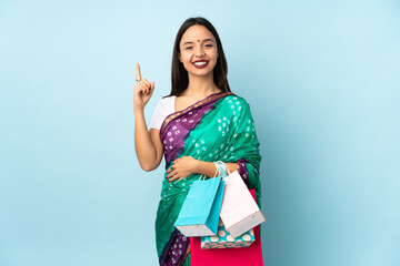 Young Indian woman with shopping bags pointing up a great idea