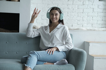 Happy woman in headphones looking at camera, enjoying video meeting with friends and colleagues,...
