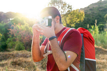 Naklejka premium Hiker taking a picture with his camera. Holidays in nature. Photographer concept.