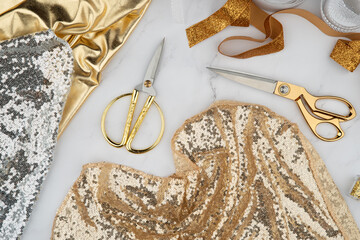 Cut and sew customized garments, sewing accessories. Gold scissors, threads, fabrics on a marble table. Sewing feminine, festive, glamorous, evening, wedding dresses, bridesmaids dress.