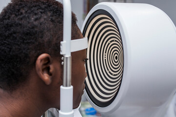 Black woman in optometry cabinet using a modern corneal topographer