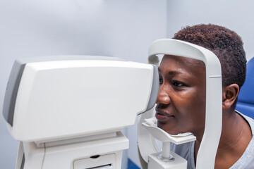 Black woman in optometry cabinet using a retinograph